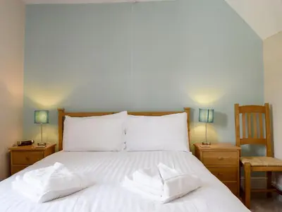 a bedroom with a bed with white sheets and two pillows at Millie's Cottage in Keswick