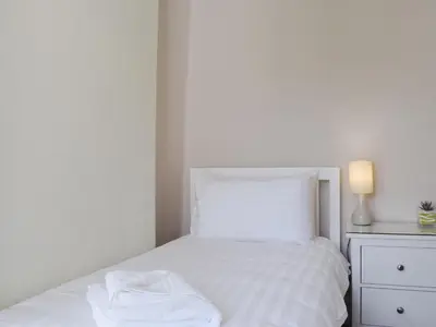 a bedroom with a bed with white sheets and a lamp at Millie's Cottage in Keswick