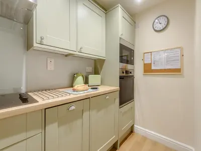 a kitchen with white cabinets and a clock on the wall at Kissing Gate in Keswick