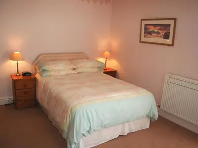 a bedroom with a bed and two night stands with lamps at Kingstarn in Keswick