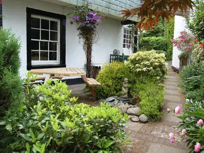 a garden with a wooden bench in front of a house at Acorn Lodge Cottage in Keswick