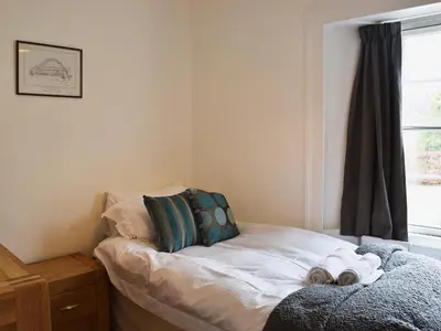 a small bed in a room with a window at Acorn Lodge Cottage in Keswick