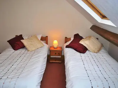 two beds in a room with a lamp on a night stand at Alvamere in Keswick