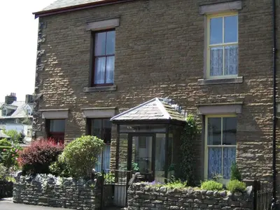 a brick house with windows and a stone wall at The Ivy Cottage in Keswick