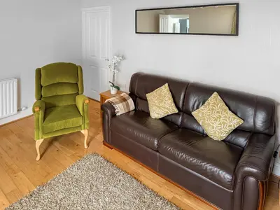 a leather couch and a green chair in a living room at 1 Windsor House in Keswick