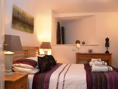 a bedroom with a bed and a dresser with towels at 1 Windsor House in Keswick
