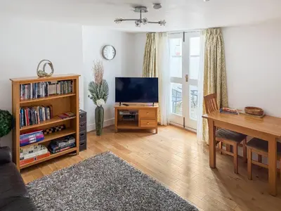 a living room with a tv and a table and a desk at 1 Windsor House in Keswick