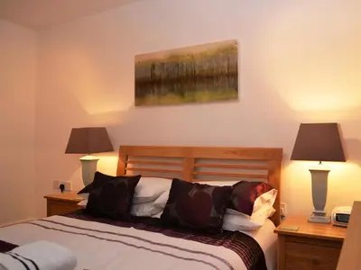 a bedroom with a bed with two lamps and a painting at 1 Windsor House in Keswick