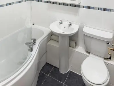 a white bathroom with a toilet and a sink at 1 Windsor House in Keswick