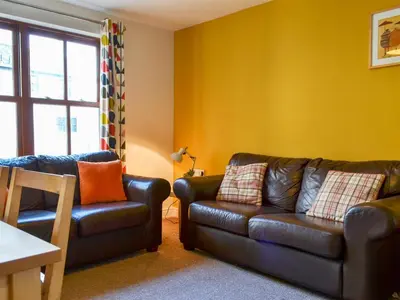 a living room with a leather couch and a chair at Bleaberry- Hewetson Court in Keswick