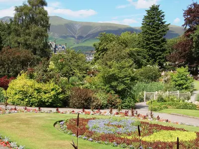 a garden with a flower bed with mountains in the background at Helvellyn House Apartment in Keswick