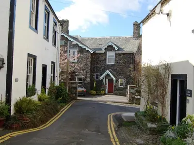 an old stone house with a red door on a street at 3 The Hollies in Keswick