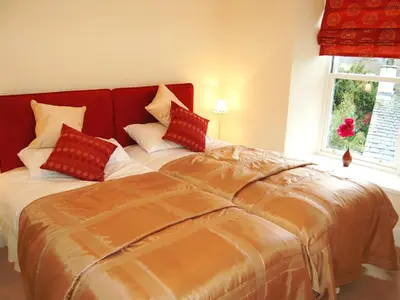 a bedroom with a large bed with red pillows at 3 The Hollies in Keswick