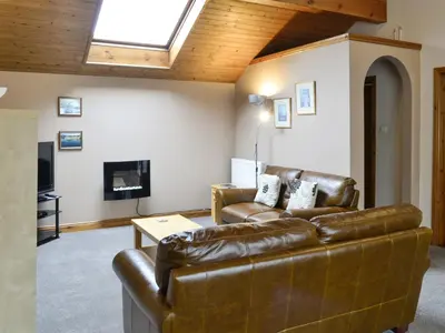 a living room with a leather couch and a television at Wickhams View in Keswick
