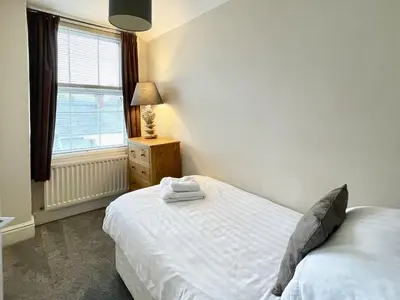 a bedroom with a white bed and a window at High Style Apartment in Keswick