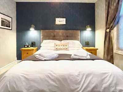 a bedroom with a large white bed with blue walls at High Style Apartment in Keswick