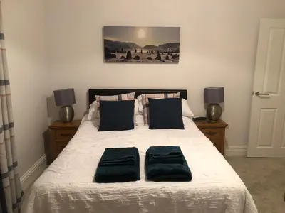 a bedroom with a bed with two black pillows at 2 Windsor House in Keswick