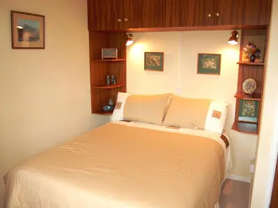 a bedroom with a bed with white sheets and wooden shelves at Peel Wyke in Keswick