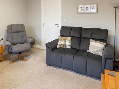 a black couch and a chair in a living room at Limetrees in Keswick