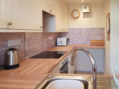 a kitchen with white cabinets and a sink at Limetrees in Keswick