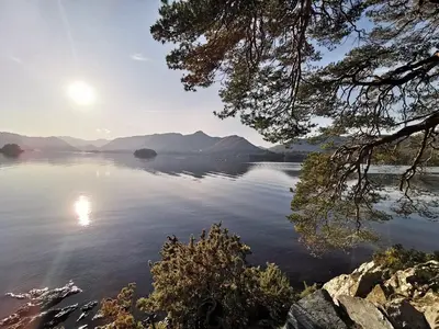 a view of a large body of water with the sun setting at Limetrees in Keswick
