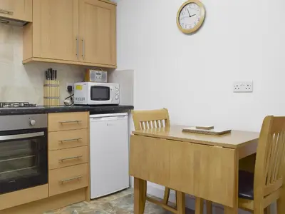 a kitchen with a table and a clock on the wall at Laal Yan in Keswick