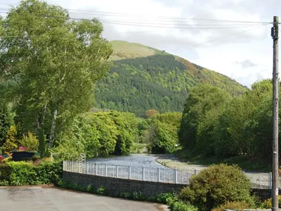 a river with a fence next to a mountain at Laal Yan in Keswick