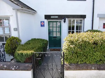 a white house with a green door and bushes at Laal Yan in Keswick