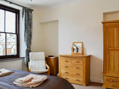 a bedroom with a bed and a dresser and a chair at Green Ghyll in Keswick
