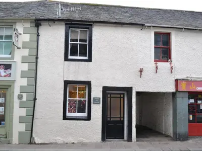 a white building with a black door on a street at Uncle's Cottage in Keswick