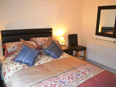 a bedroom with a bed with two pillows and a mirror at Uncle's Cottage in Keswick