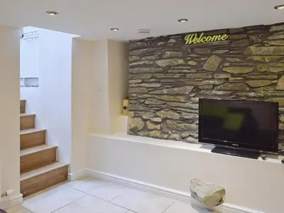 a living room with a tv on a stone wall at Falcon Crag in Keswick