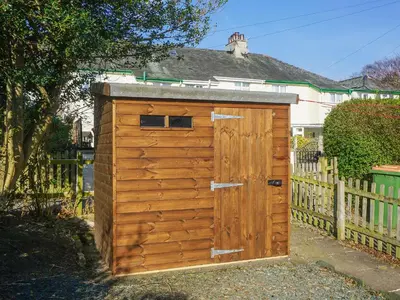 a wooden outhouse with a wooden door in front of a fence at Valentine Cottage in Keswick