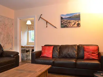 a living room with a brown leather couch with red pillows at Riverbank in Keswick