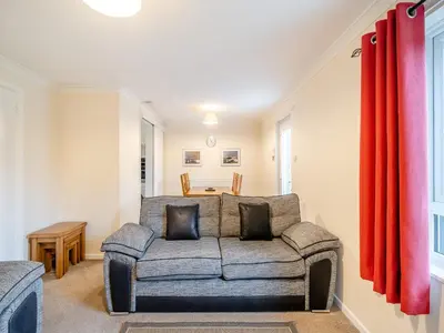 a living room with a couch and red curtains at Barleycorn in Keswick