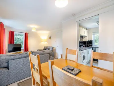a living room with a dining room table and a kitchen at Barleycorn in Keswick