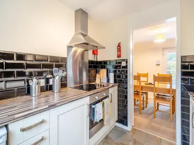 a kitchen with a stove top oven next to a dining room at Barleycorn in Keswick
