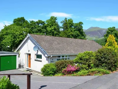 a small white house with a green garage at Haystacks in Keswick