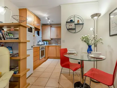 a small kitchen with a table and red chairs at Chaucer Lodge Apt 1 in Keswick