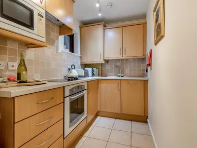 a small kitchen with wooden cabinets and a sink at Chaucer Lodge Apt 1 in Keswick