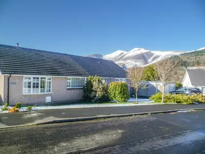 a house on a street with mountains in the background at The Bolthole Formerly Candlemas in Keswick
