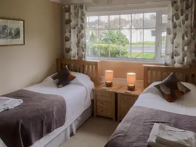 a bedroom with two beds and a window at The Bolthole Formerly Candlemas in Keswick