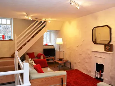 a living room with a staircase and a fireplace at 4 The Plosh in Keswick