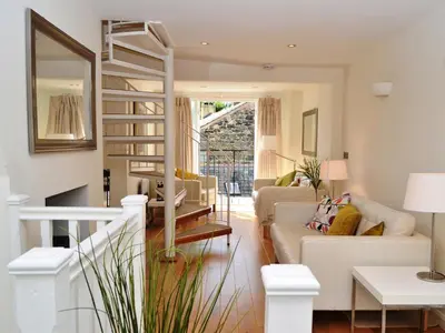 a living room with white furniture and a spiral staircase at 5 The Plosh in Keswick
