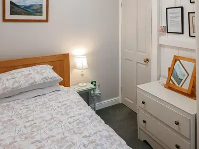 a bedroom with a bed and a table with a mirror at 1 Tower Cottage in Portinscale