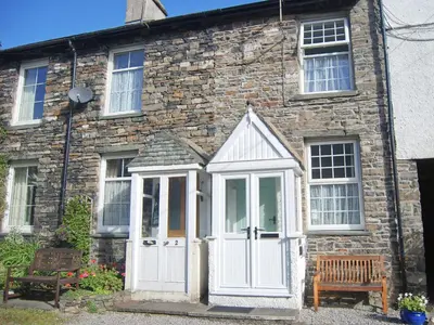 an old stone house with a white door at 1 Tower Cottage in Portinscale