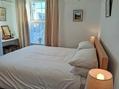 a bedroom with a white bed with a window at 1 Tower Cottage in Portinscale