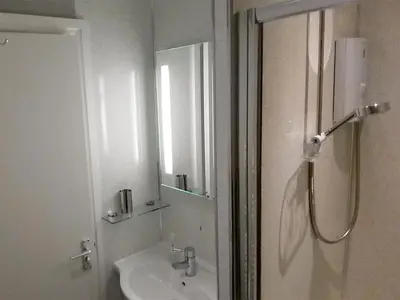 a white bathroom with a shower and a sink at Causey Cottage in Keswick