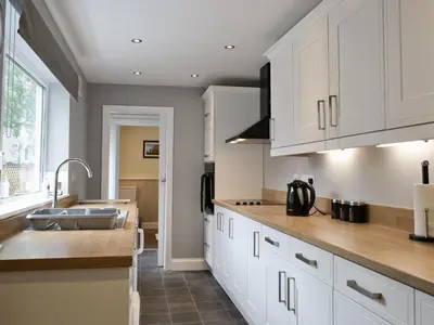 a kitchen with white cabinets and a sink at Causey Cottage in Keswick