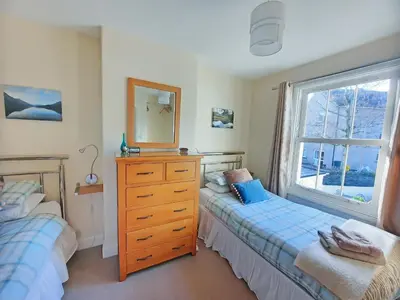 a bedroom with two beds and a dresser and a window at Causey Cottage in Keswick